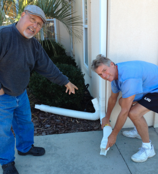 Rosario Oddo, left, and Jim Cepko, residents of the Lakes of Lockwood Community in Brunswick County are disconnecting a gutter downspout so that it will no longer downpour directly onto the driveway.