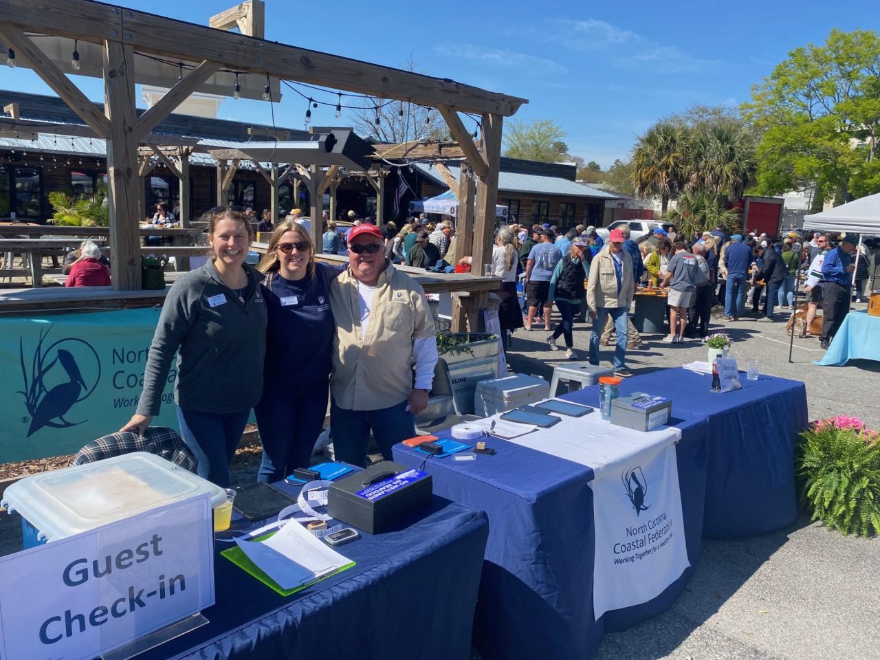 An image of staff from the Federation's Southeast Office standing in front of a table at the 2023 Roast for the Coast at Waterman's Brewing