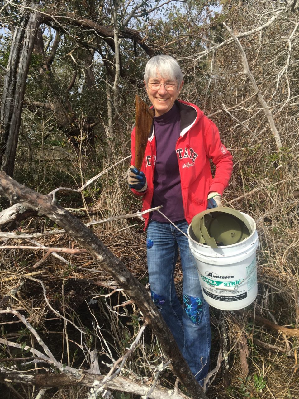A volunteer at Hoop Pool Creek gathering plastic and wooden debris from the trail.